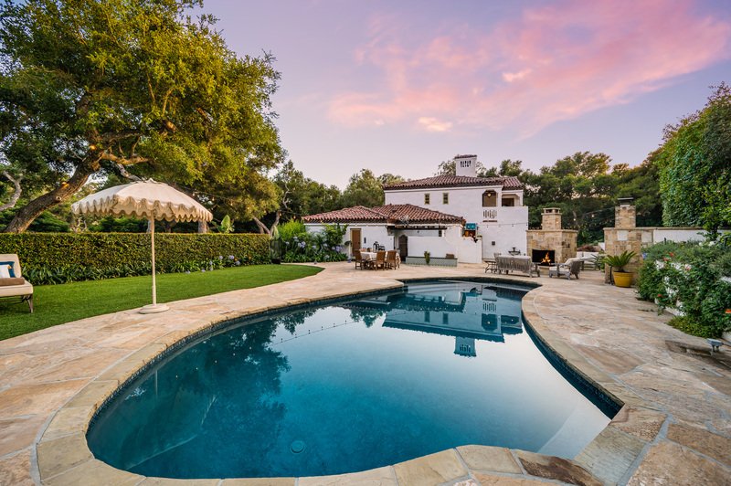 Alberca de concreto con acabados modernos en el patio trasero de una amplia residencia