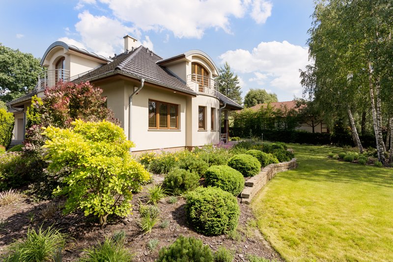 Casa amplia con jardín grande y arbustos